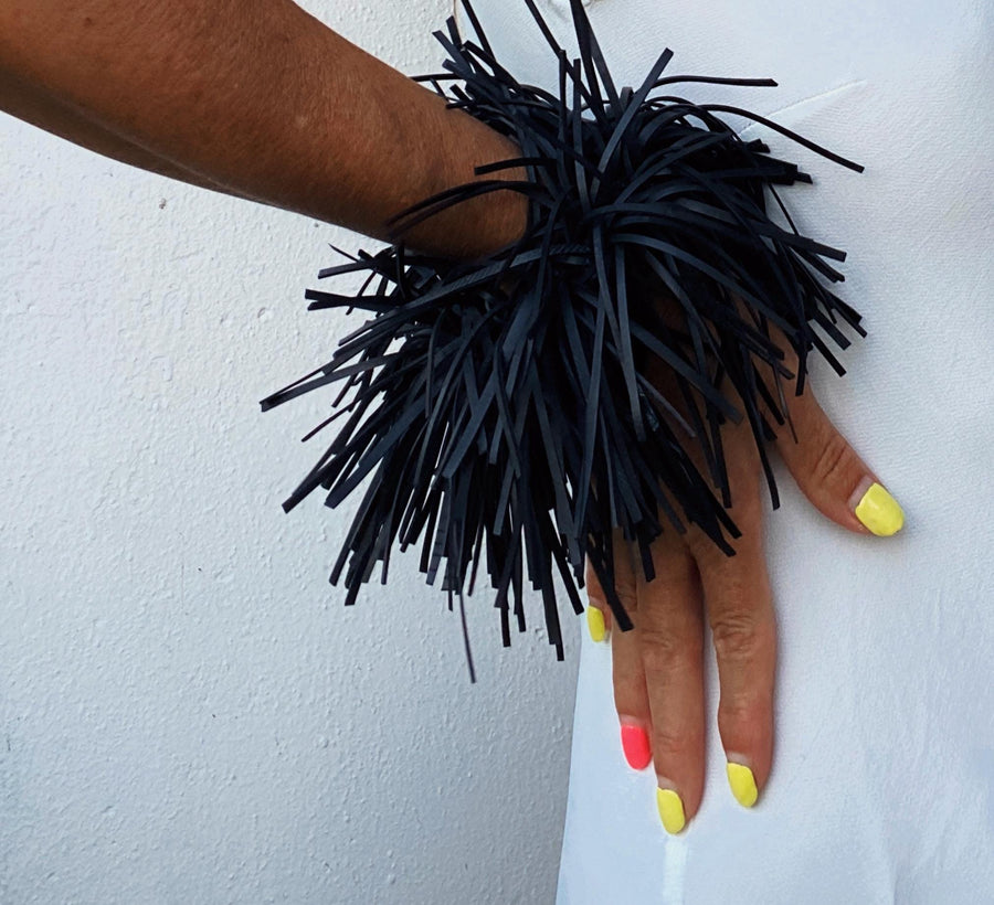 model wears quirky, bold, large, black statement bracelet made from upcycled bicycle inner tube strips