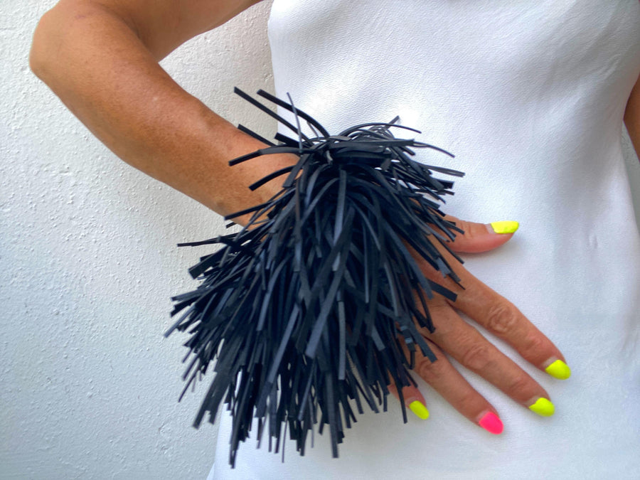 model wears quirky, bold, large, black statement bracelet made from upcycled bicycle inner tube strips