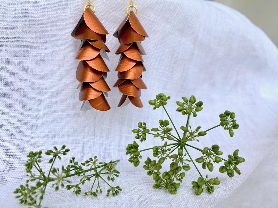 copper coloured cascade earrings made from upcycled nespresso capsule aluminium on a white background and green flower