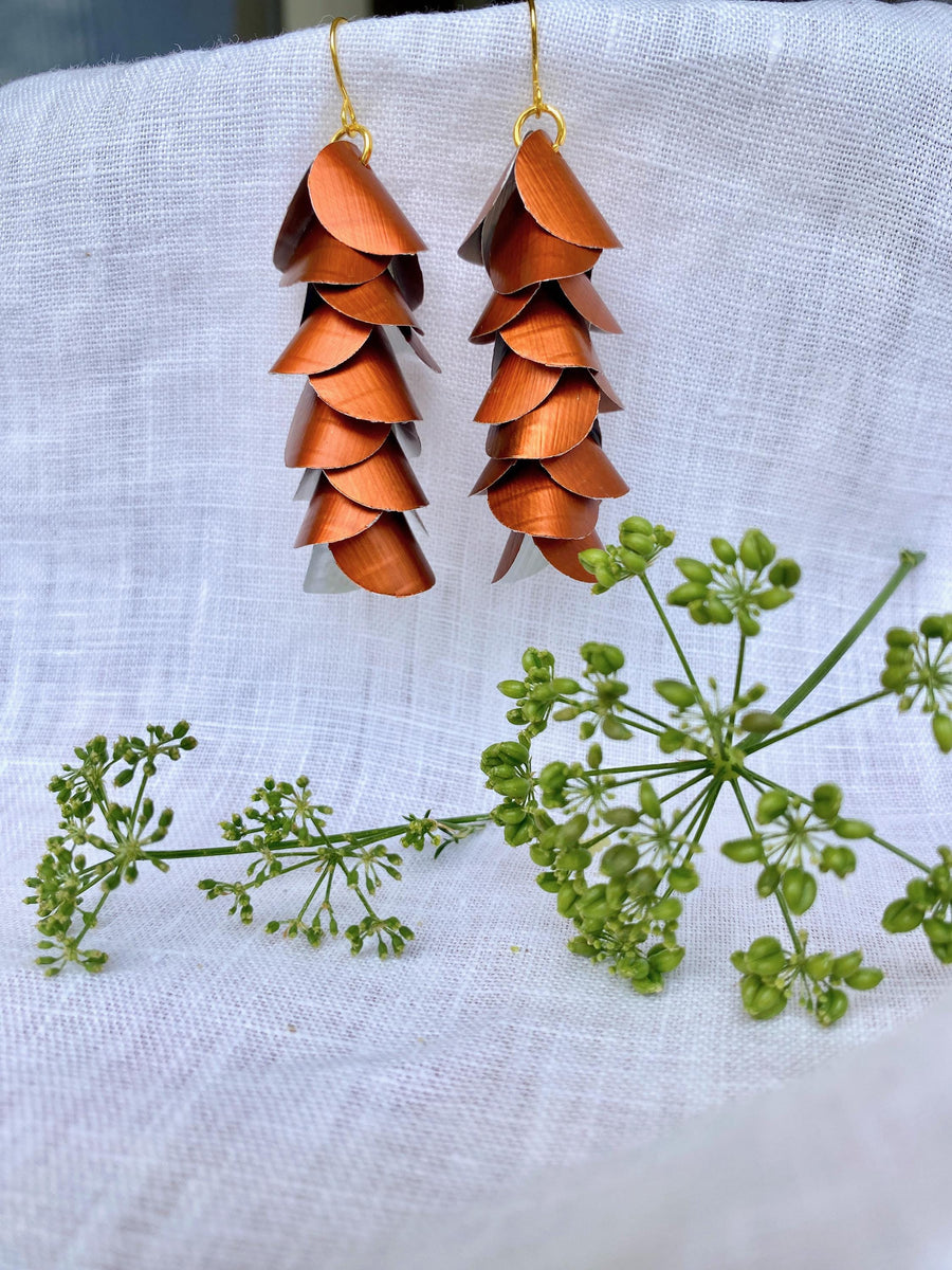 copper coloured cascade earrings made from upcycled nespresso capsule aluminium on a white background and green flower