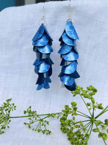 blue cascade earrings made from upcycled nespresso capsules aluminium on a white linen background and green flower