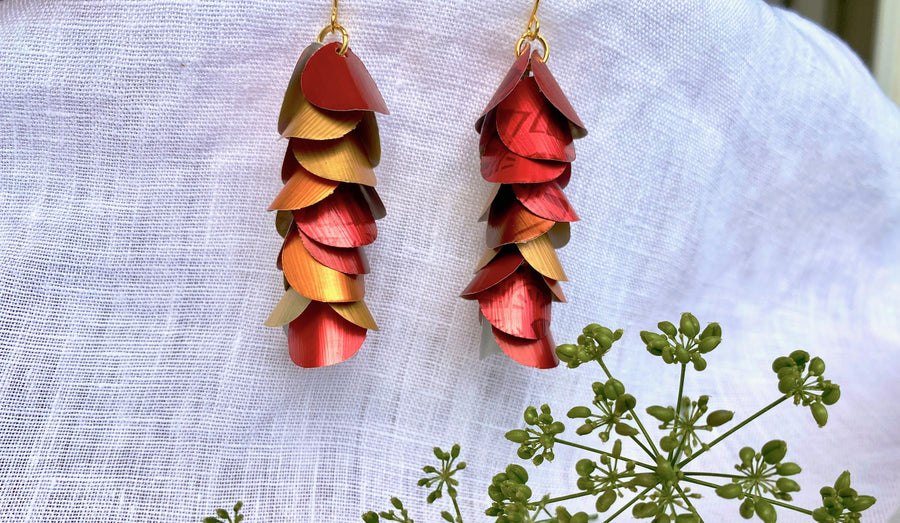 red orange gold cascade earrings made from upcycled nespresso capsule aluminium on a white linen background and green flower