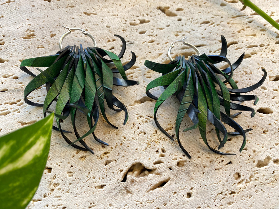 Pair of green, curly statement earrings made from upcycled bicycle inner tube rubber by laura zabo on a marble display