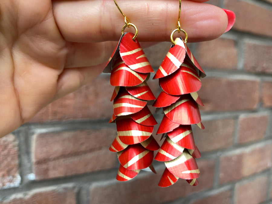 red gold cascade earrings made from upcycled nespresso capsules aluminium on a brick wall background