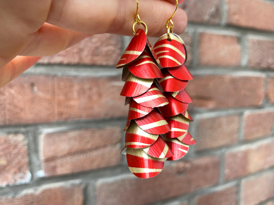 red gold cascade earrings made from upcycled nespresso capsules aluminium on a brick wall background