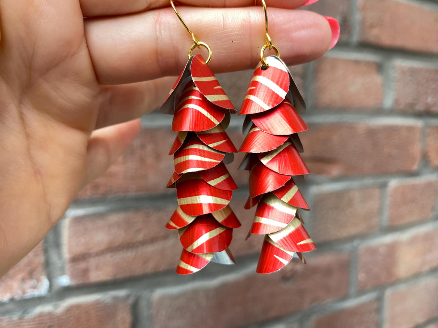 red gold cascade earrings made from upcycled nespresso capsules aluminium on a brick wall background