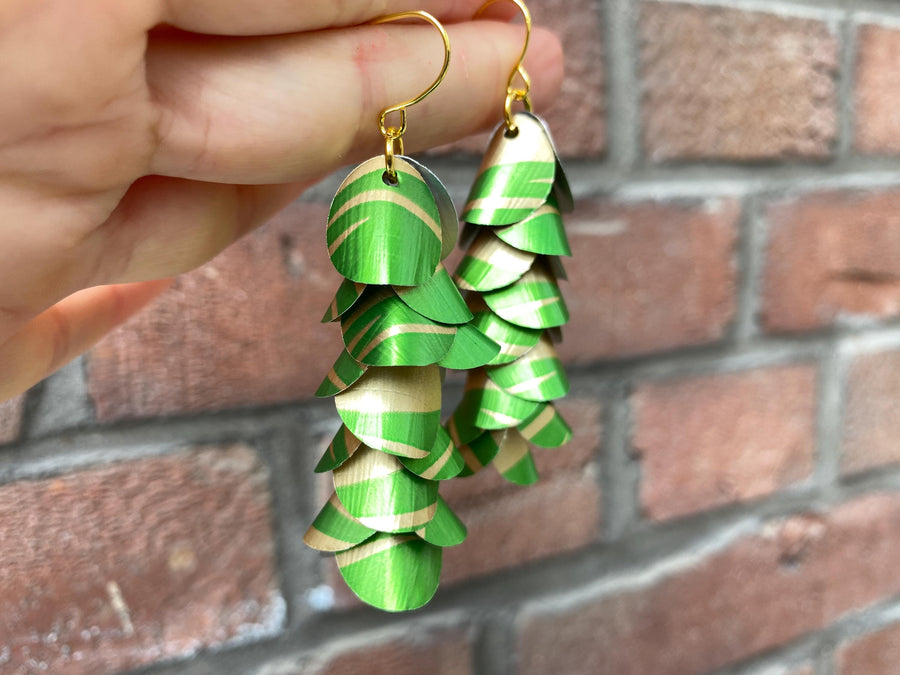 lime green gold coloured cascading earrings made from upcycled nespresso pods on a brick wall background