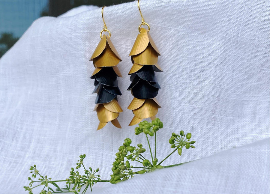 gold-black cascading earrings made from upcycled nespresso capsule aluminium on a white linen background and green flower