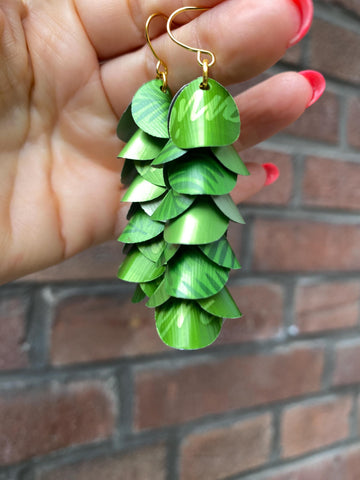 bright lime green cascade earrings made from upcycled nespresso capsule aluminium on brick wall background