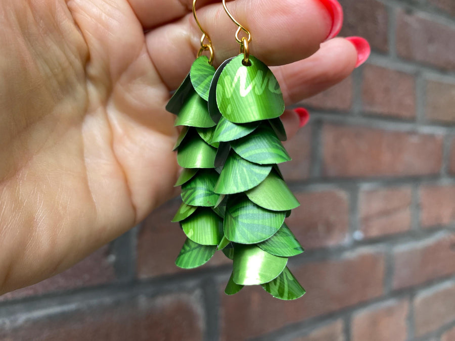 bright lime green cascade earrings made from upcycled nespresso capsule aluminium on brick wall background