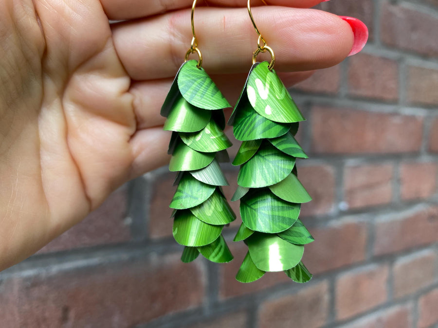 bright lime green cascade earrings made from upcycled nespresso capsule aluminium on brick wall background