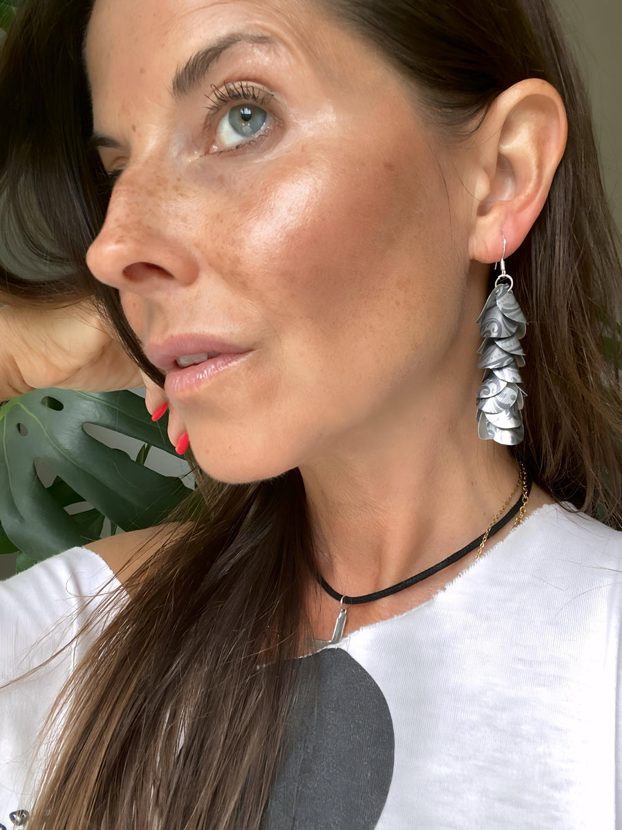 model wears silver coloured cascade earrings made from upcycled nespresso pod aluminium