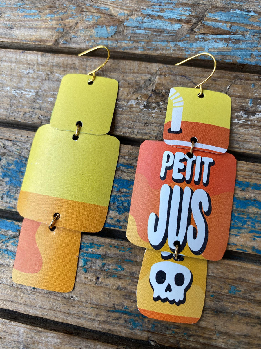 pair of yellow orange geometric earrings with text and skull design made from an upcycled beer can on a rustic wooden background