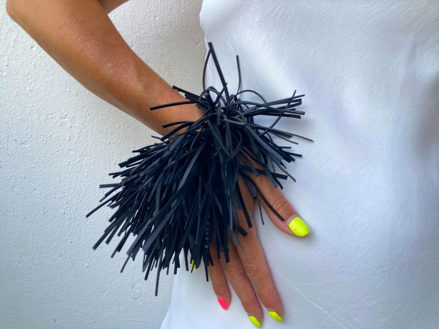 model wears quirky, bold, large, black statement bracelet made from upcycled bicycle inner tube strips