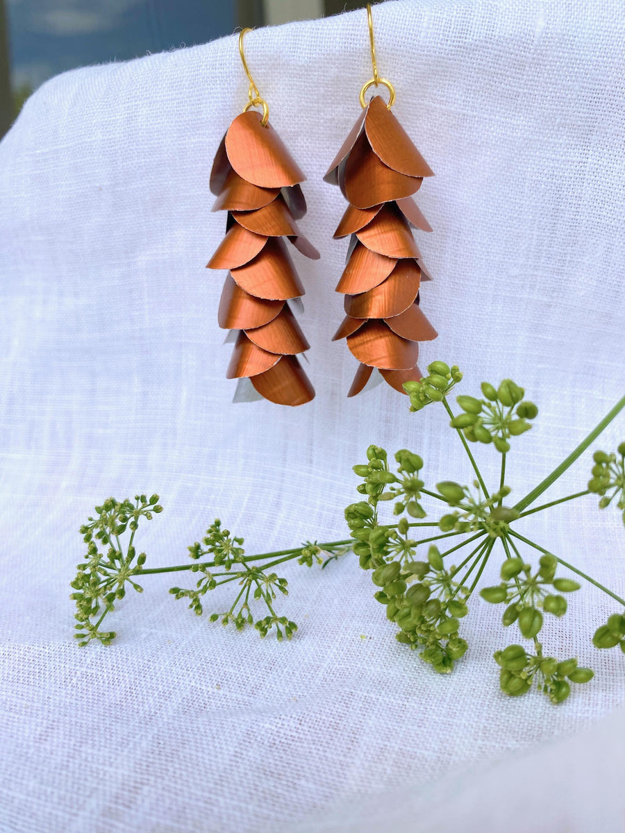 copper coloured cascade earrings made from upcycled nespresso capsule aluminium on a white background and green flower
