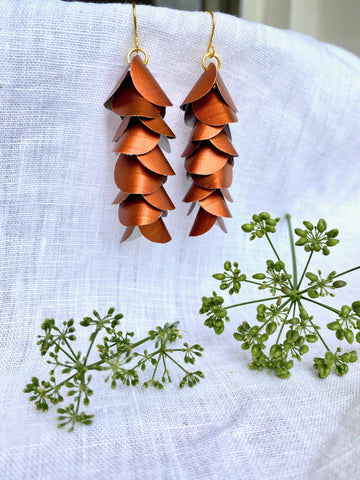 copper coloured cascade earrings made from upcycled nespresso capsule aluminium on a white background and green flower