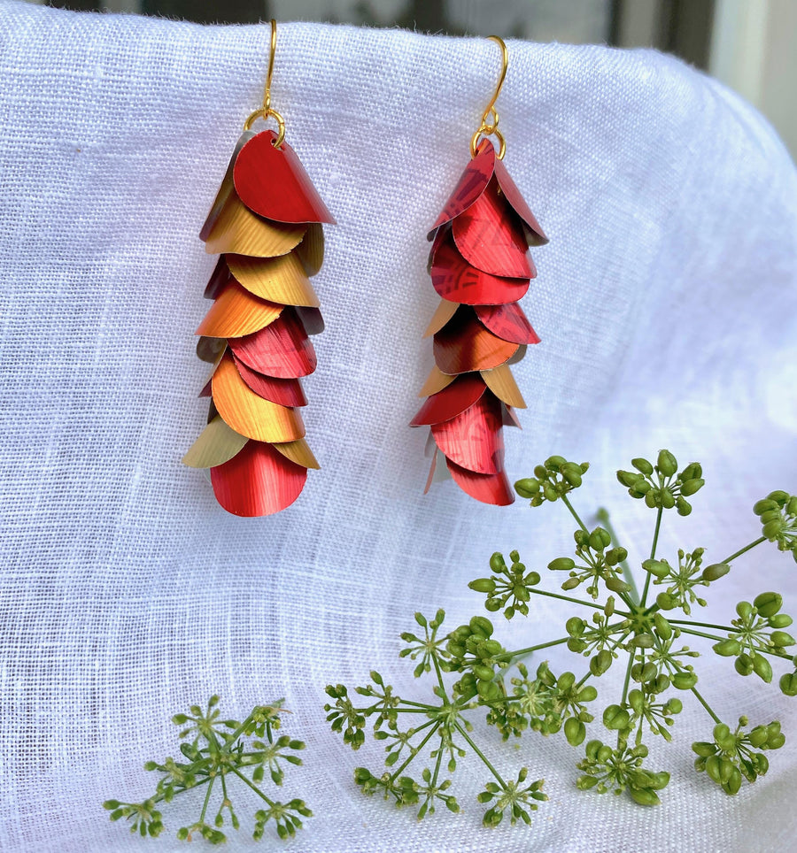 red orange gold cascade earrings made from upcycled nespresso capsule aluminium on a white linen background and green flower