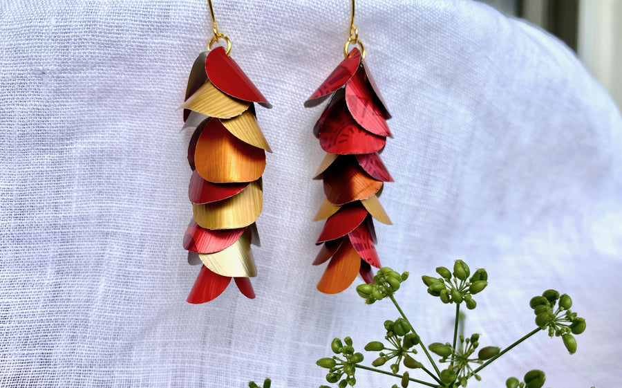 red orange gold cascade earrings made from upcycled nespresso capsule aluminium on a white linen background and green flower