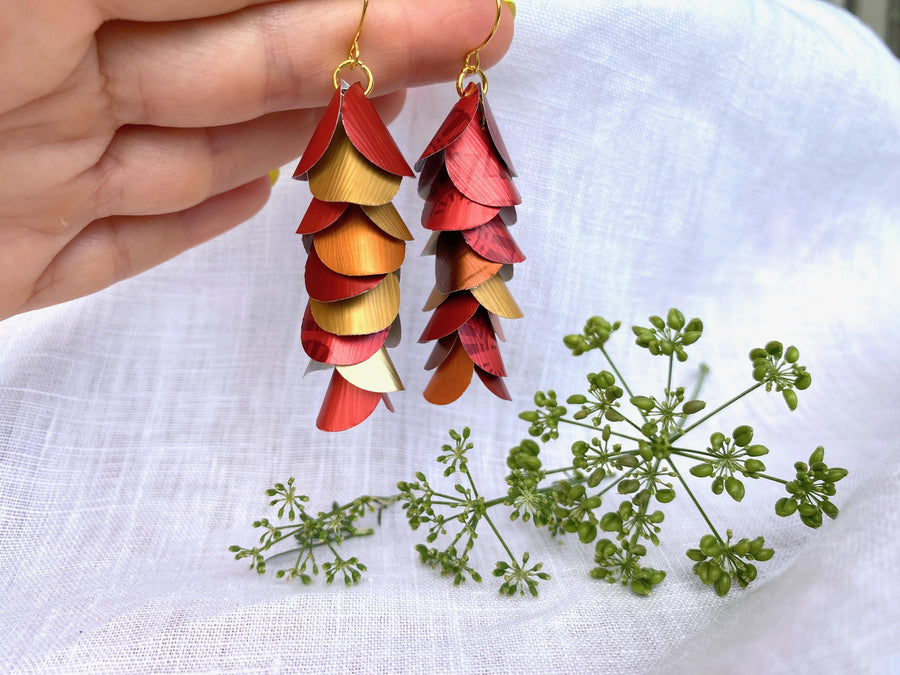 red orange gold cascade earrings made from upcycled nespresso capsule aluminium on a white linen background and green flower