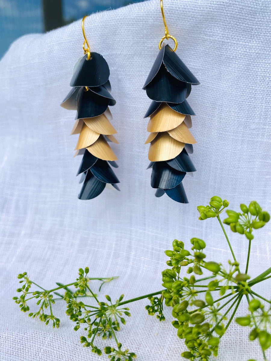 gold black cascade earrings made from upcycled nespresso capsules aluminium on a brick wall background