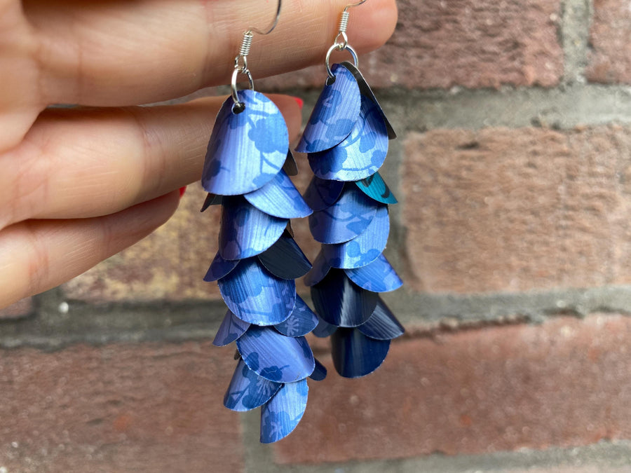 blue cascade earrings made from upcycled nespresso capsule aluminium on brick wall background