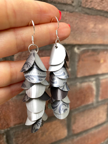 silver coloured cascade earrings made from upcycled nespresso capsules on a brick wall background