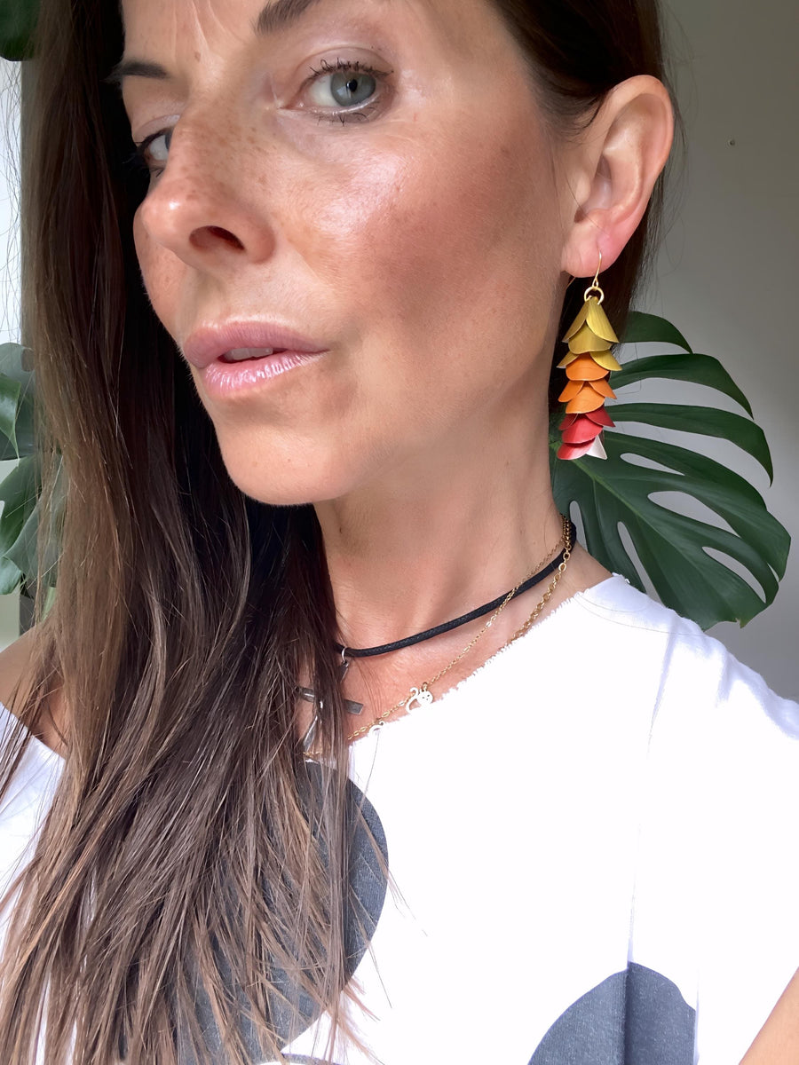 model wears sunset, sunrise themed gold-orange-red earrings made from upcycled nespresso pod aluminium