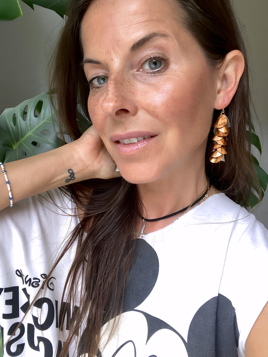 model wears bronze gold cascade earrings made from upcycled nespresso pod aluminium