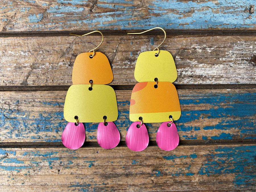 pair of orange yellow pink summer earrings made from upcycled beer can and Nespresso capsules on a rustic wooden background