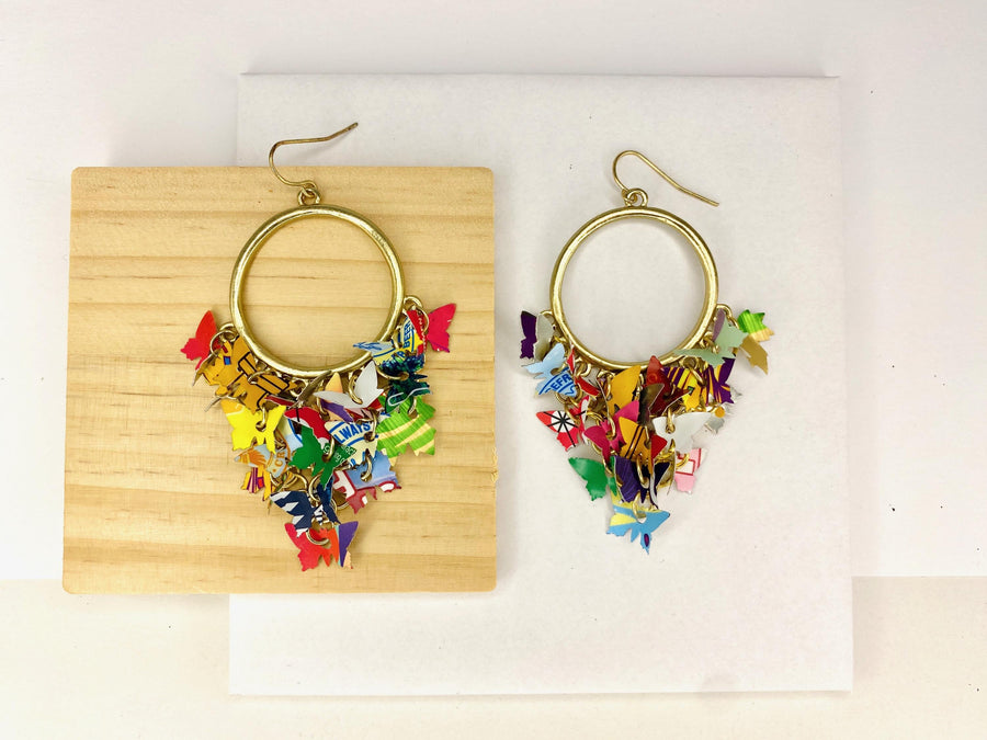 golden hoop earrings with butterflies made from upcycled beer cans and soda cans on a white and wooden background