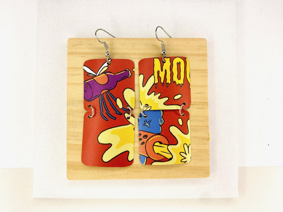 comic, graffiti style earrings made from an upcycled craft beer can in orange, yellow colours, on a wooden and white background
