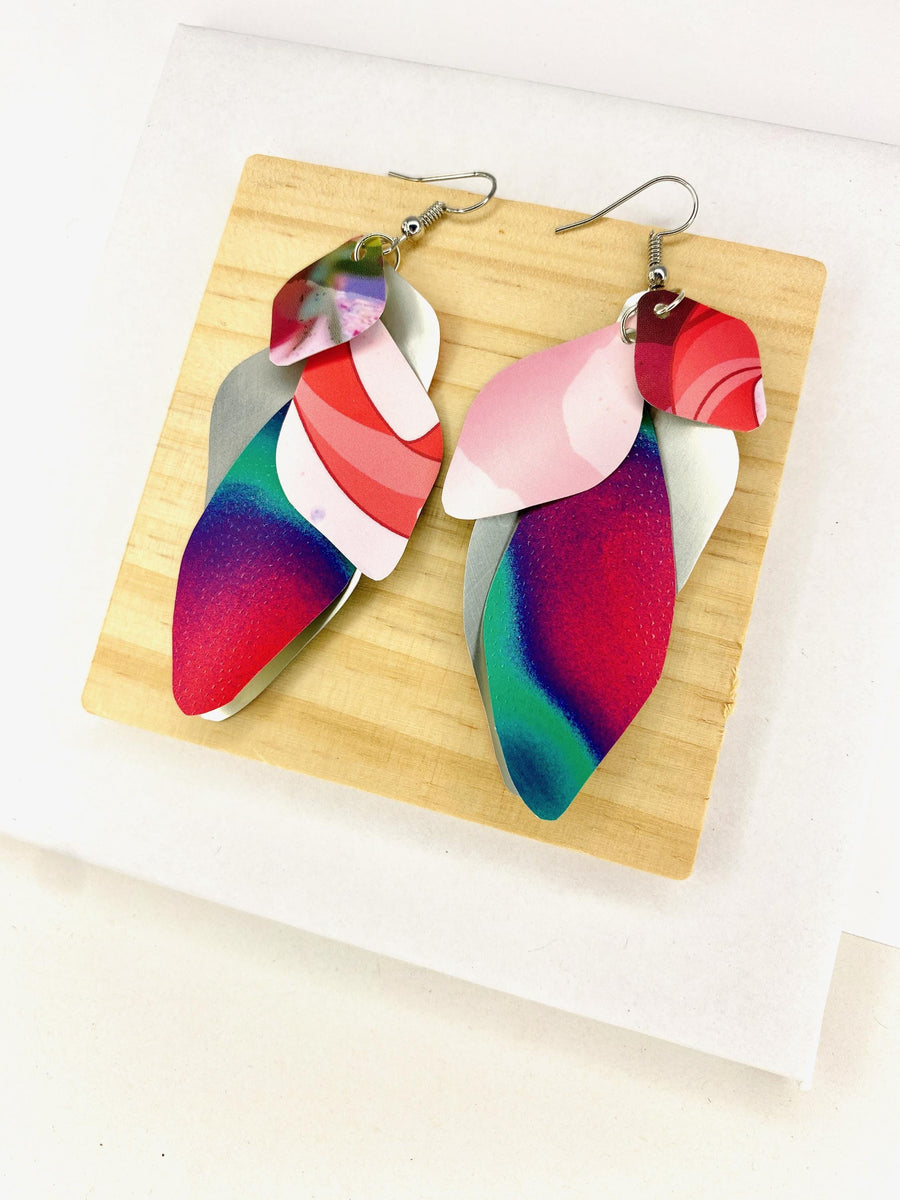 Pink purple green cascade earrings made from upcycled craft beer cans by Laura Zabo on a wooden and white background