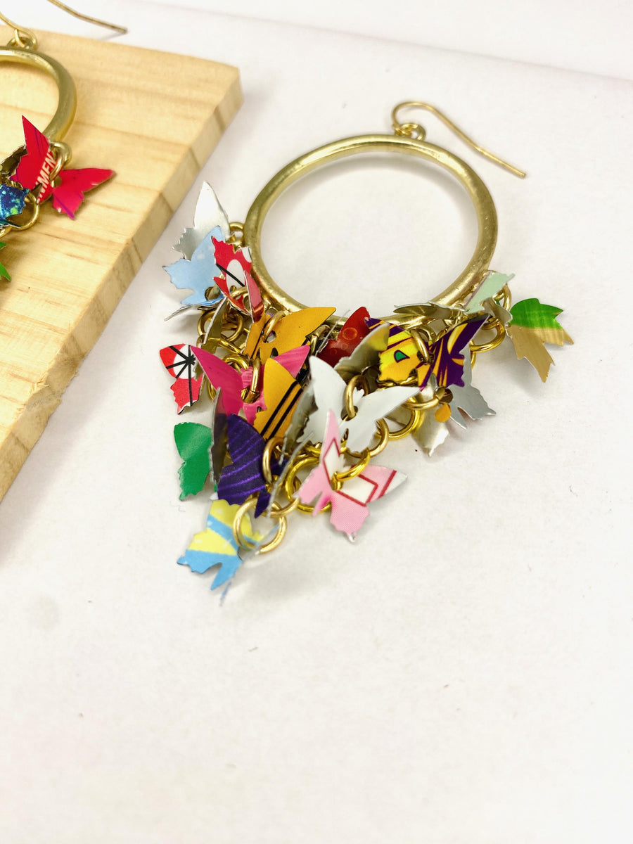 golden hoop earrings with butterflies made from upcycled beer cans and soda cans on a white and wooden background