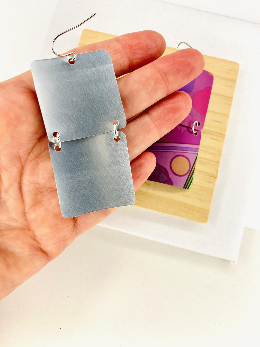 purple earrings made from upcycled craft beer can displayed in hand