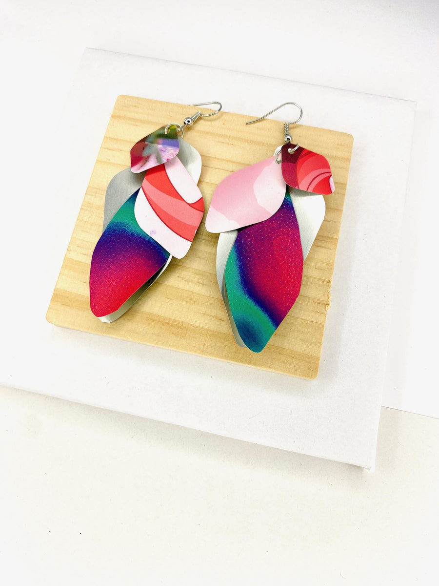Pink purple green cascade earrings made from upcycled craft beer cans by Laura Zabo on a wooden and white background