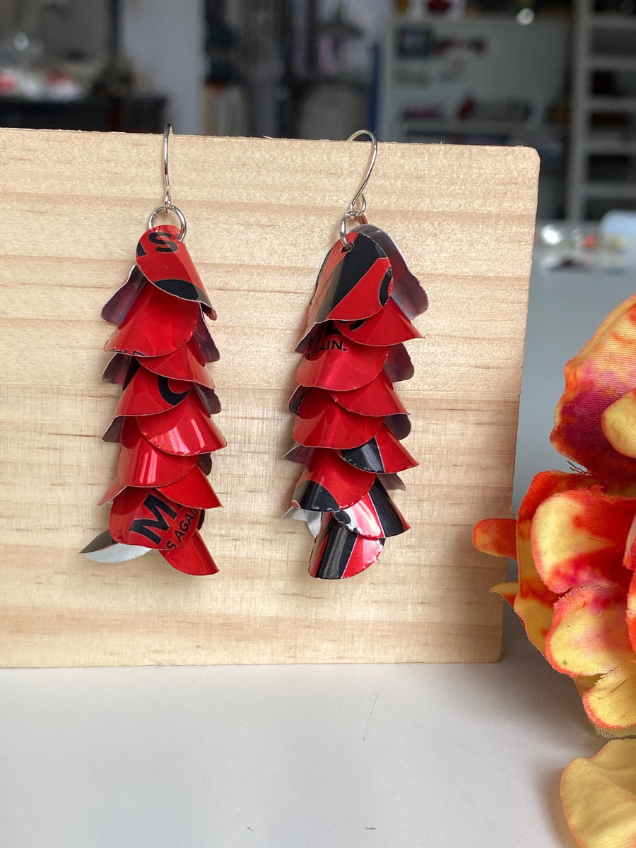 red cascade earrings made from upcycled coca cola aluminum canson a wooden background and flower decoration