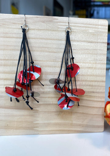 upcycled red black disc earrings on waxed cotton threads, made by Laura Zabo on a wooden background and flower decoration
