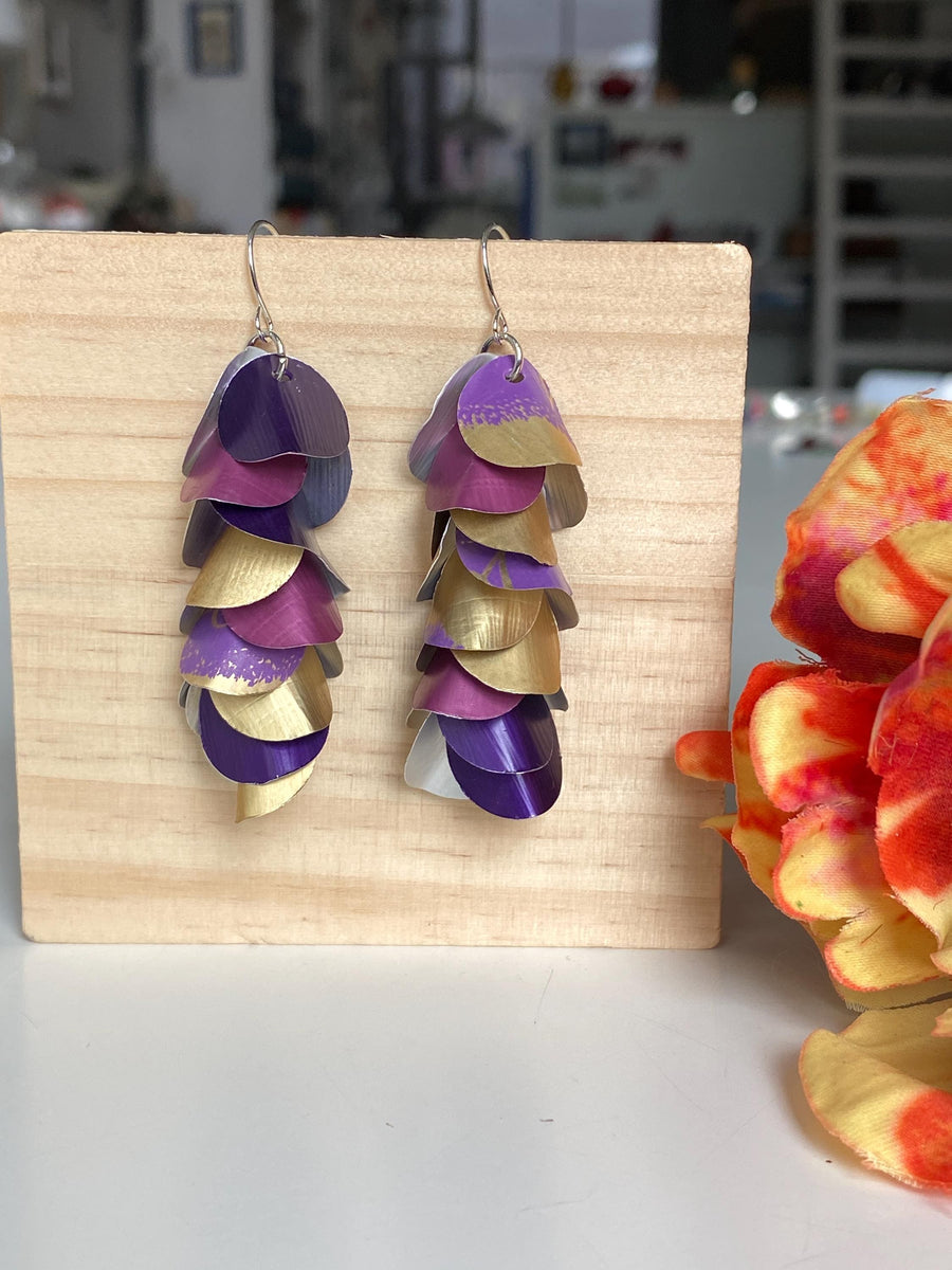gold purple cascade earrings made from upcycled nespresso pods by Laura zabo on a wooden background and a flower