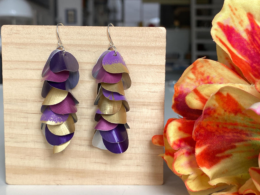 gold purple cascade earrings made from upcycled nespresso pods by Laura zabo on a wooden background and a flower
