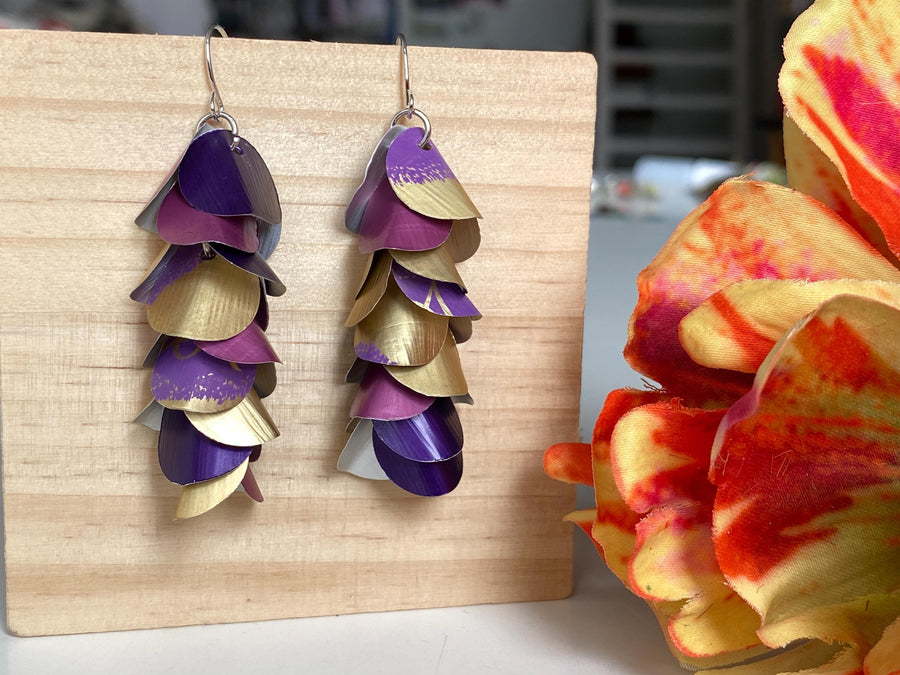 gold purple cascade earrings made from upcycled nespresso pods by Laura zabo on a wooden background and a flower