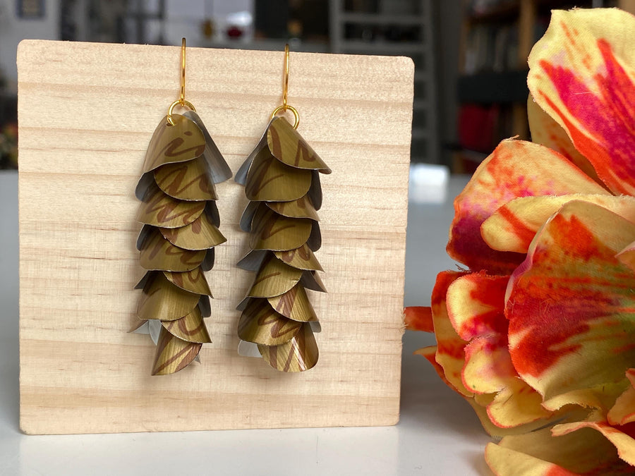 dark gold cascade earrings made from upcycled nespresso coffee pods, Nicaragua capsules by laura zabo, on a wooden background and flower decoration