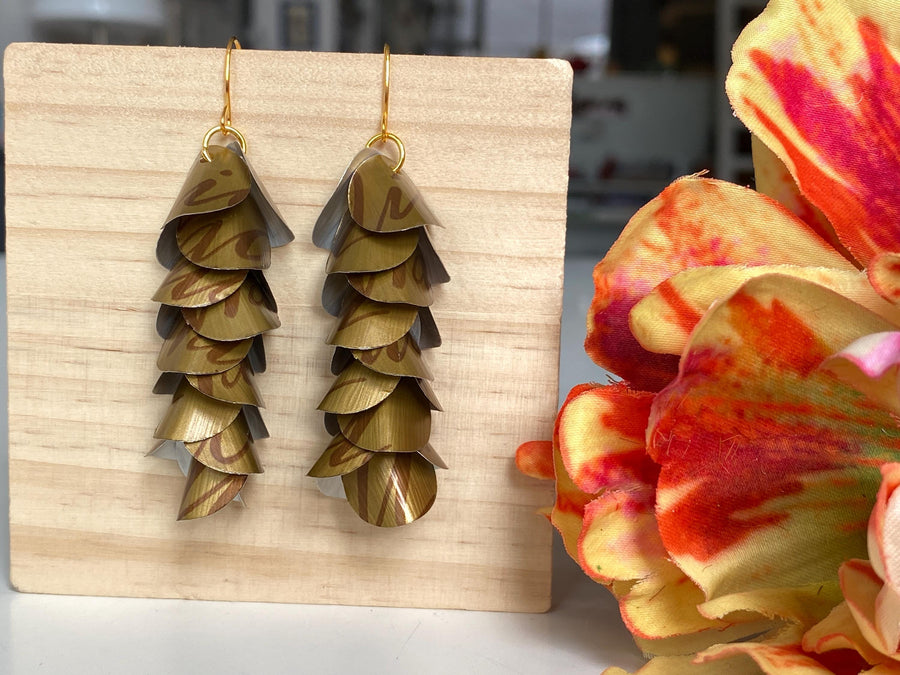 dark gold cascade earrings made from upcycled nespresso coffee pods, Nicaragua capsules by laura zabo, on a wooden background and flower decoration