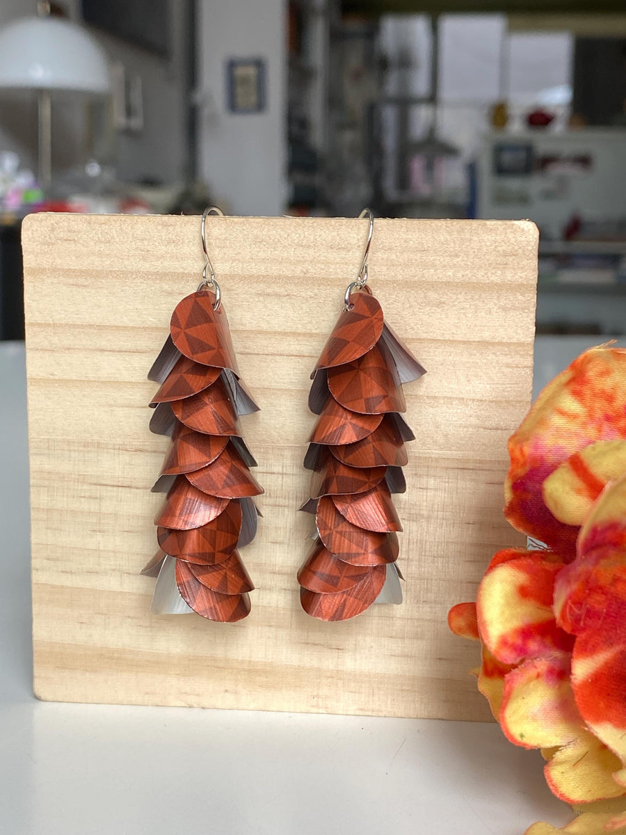 rust-copper coloured cascade earrings made from Nespresso Cape Town Lungo Capsules by Laura Zabo on a wooden background and flower decoration