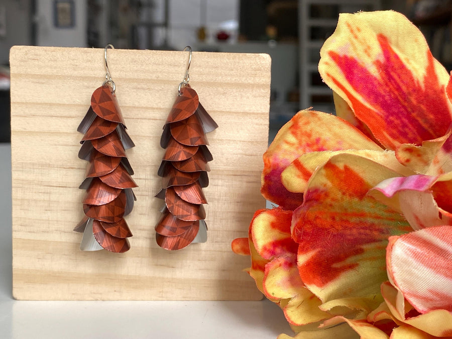 rust-copper coloured cascade earrings made from Nespresso Cape Town Lungo Capsules by Laura Zabo on a wooden background and flower decoration