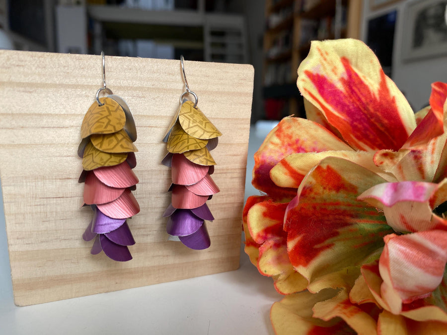 mustard peach and purple coloured cascade earrings made from repurposed nespresso coffee pods by Laura Zabo on a wooden background and flower decoration