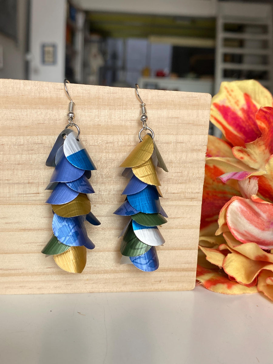 blue green gold silver cascade earrings made from upcycled nespresso capsules by laura zabo on a wooden background and flower decoration