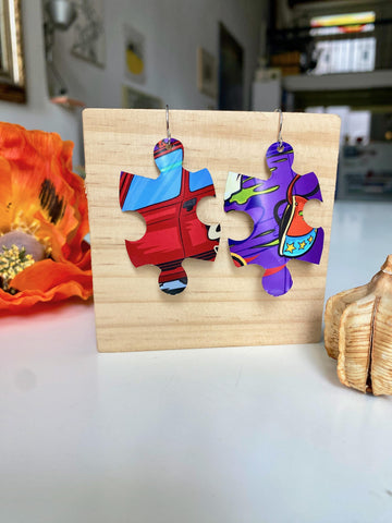 blue purple red graffiti, urban style puzzle shaped earrings made from upcycled beer can by laura zabo on a wooden background and flower decoration