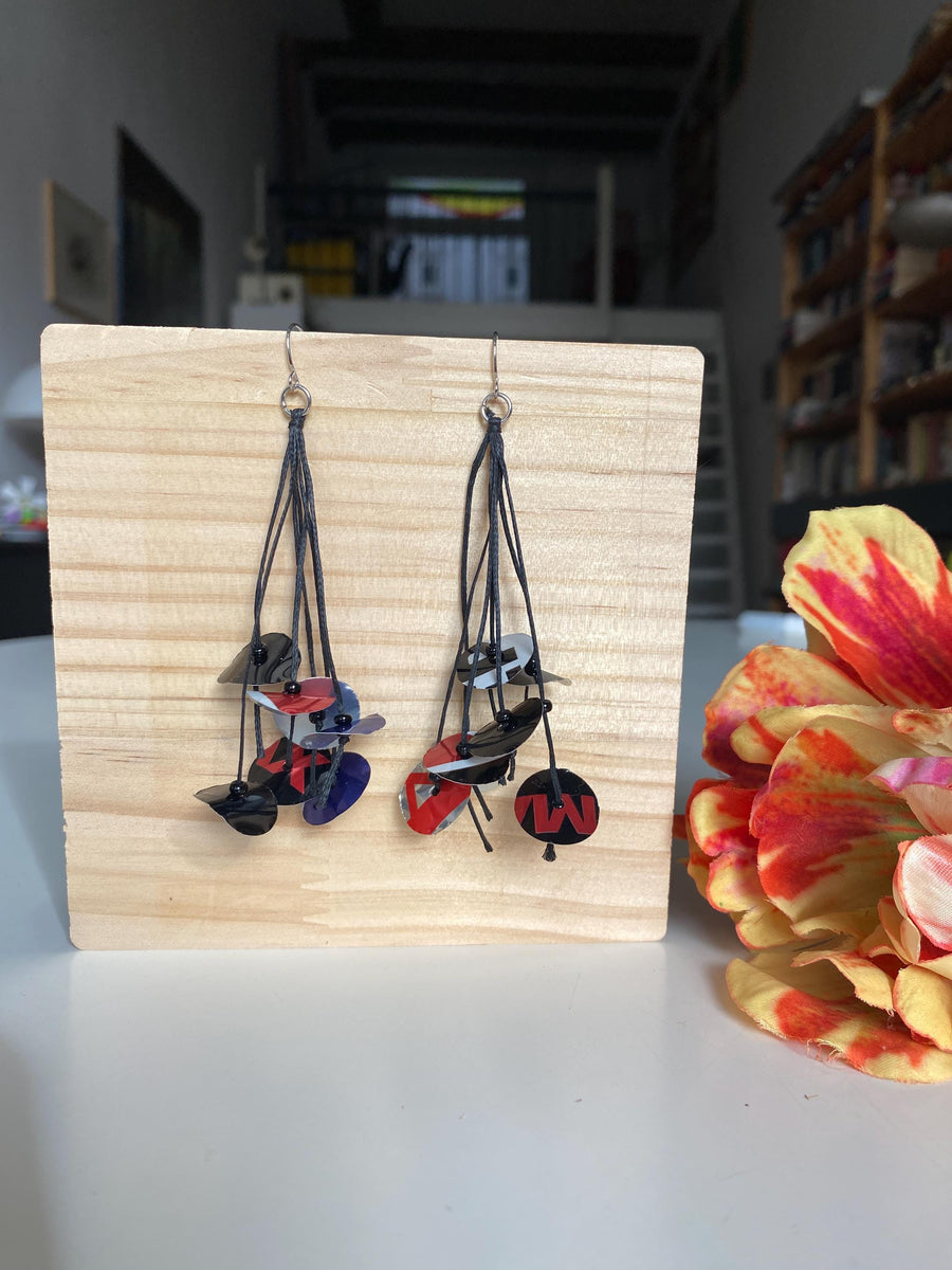 black blue red earrings on waxed cotton made from upcycled pepsi cans on a wooden background and flower decoration