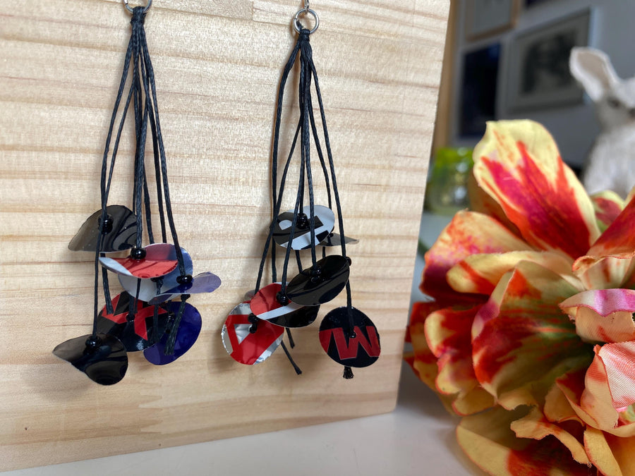 black blue red earrings on waxed cotton made from upcycled pepsi cans on a wooden background and flower decoration