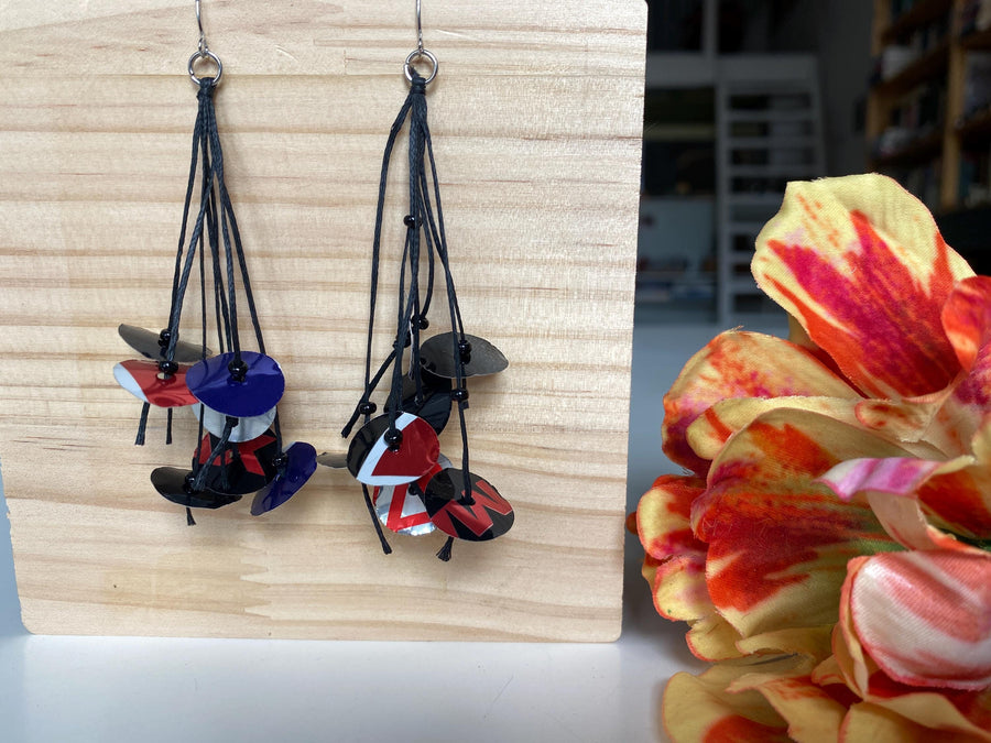 black blue red earrings on waxed cotton made from upcycled pepsi cans on a wooden background and flower decoration